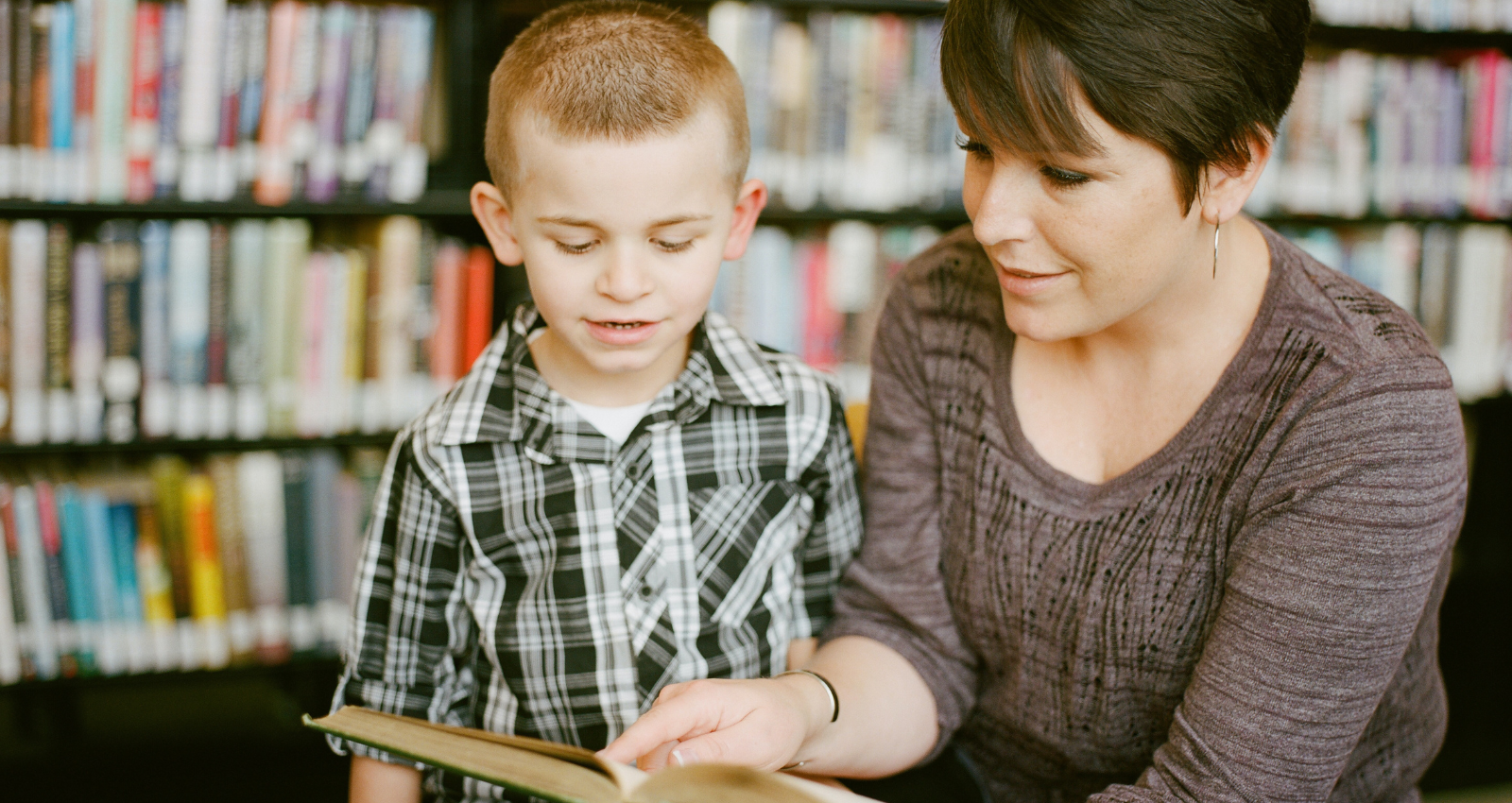 child being read to by woman in library
