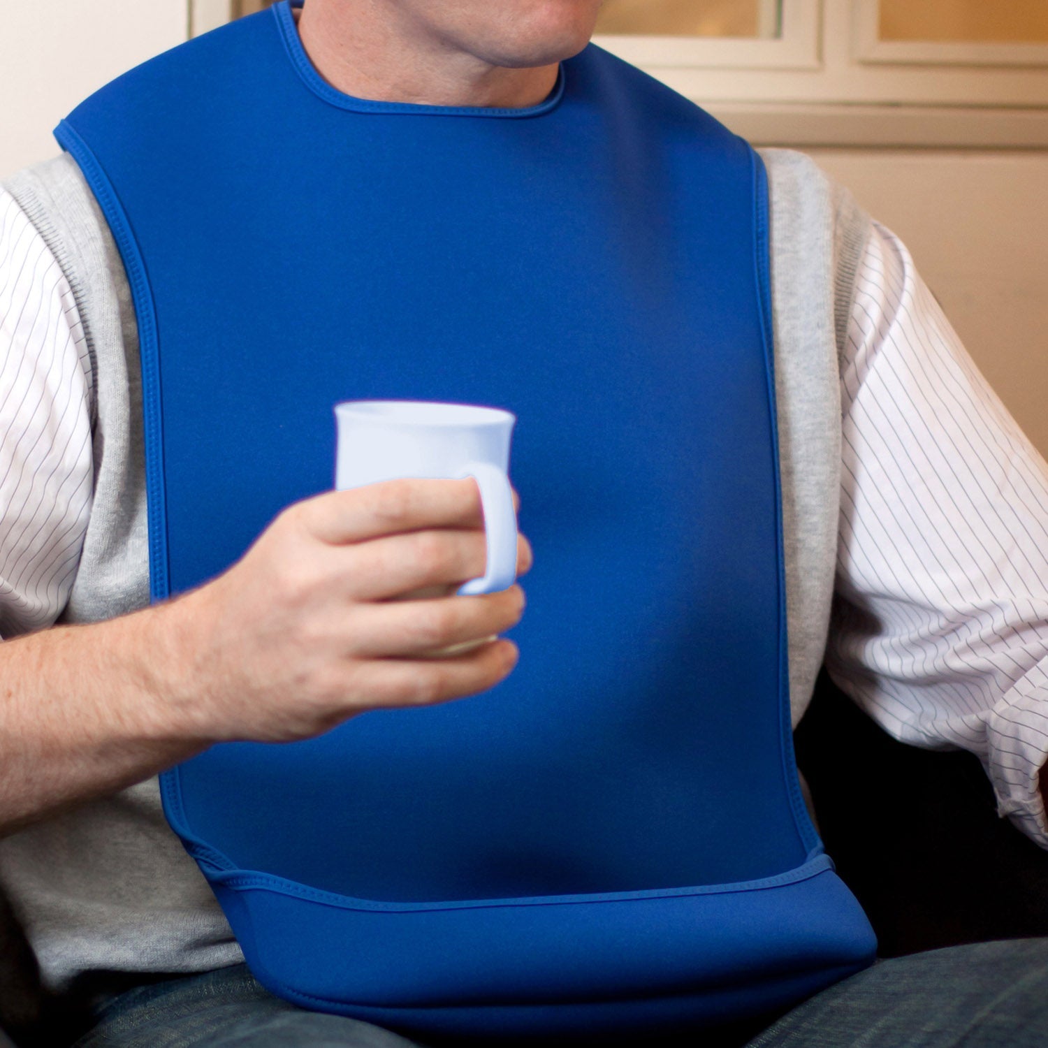 CareDesign_large_tabard_for_special_needs_adult_wearing_a_blue_bib_with_feeding_pouch